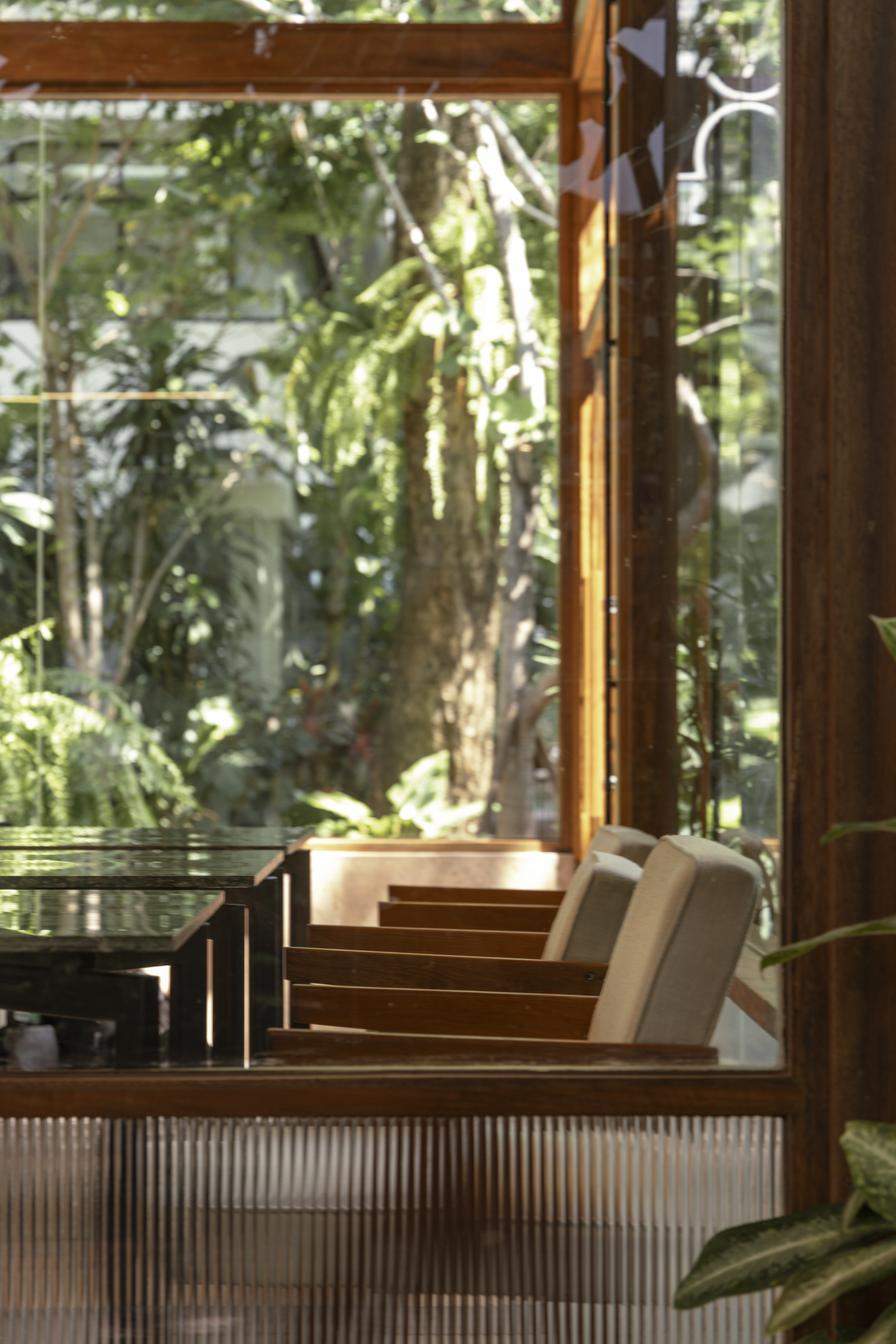 Café LOM — interior seating with lush garden through glass walls